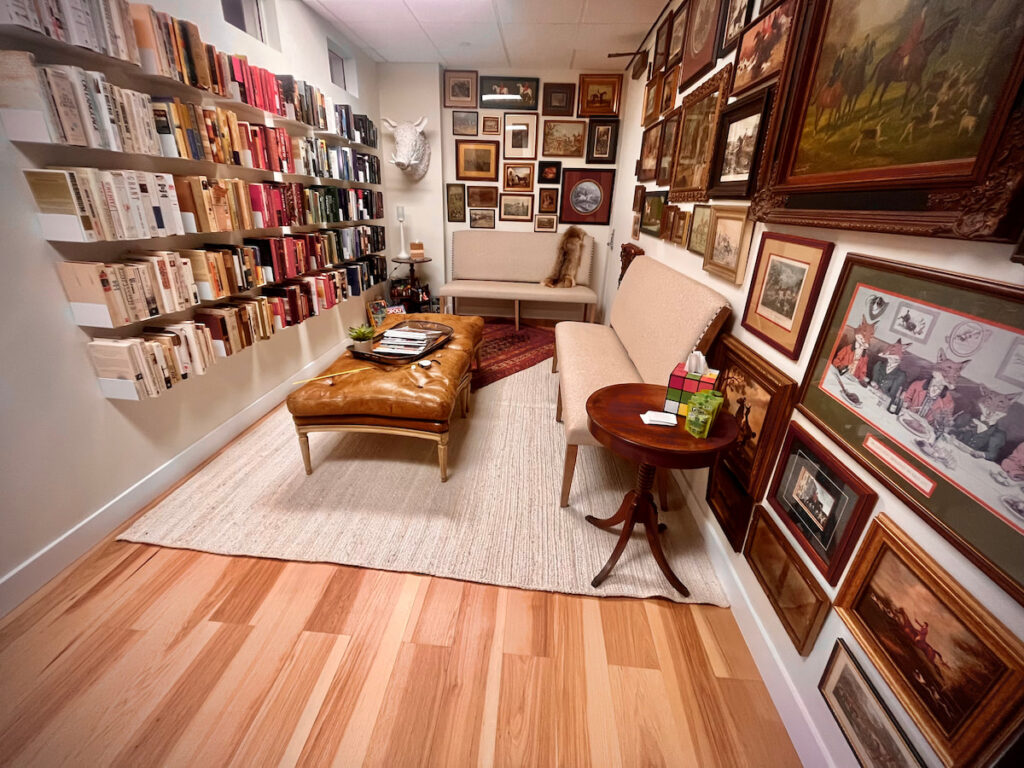 Waiting area with a leather sofa and bookshelves at Unfold Psychology Corte Madera