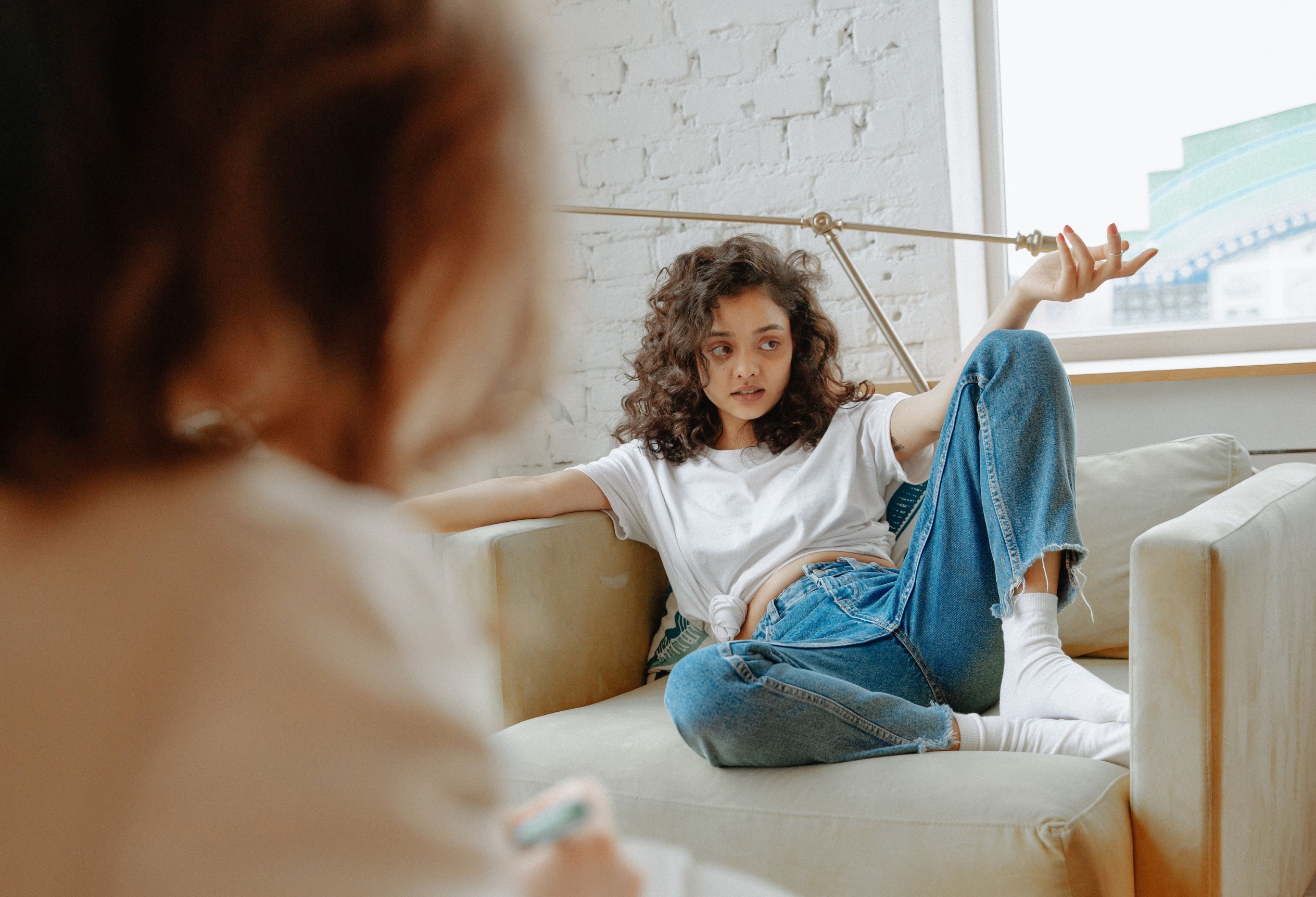 Teenager talking with a therapist on a couch, teen therapy
