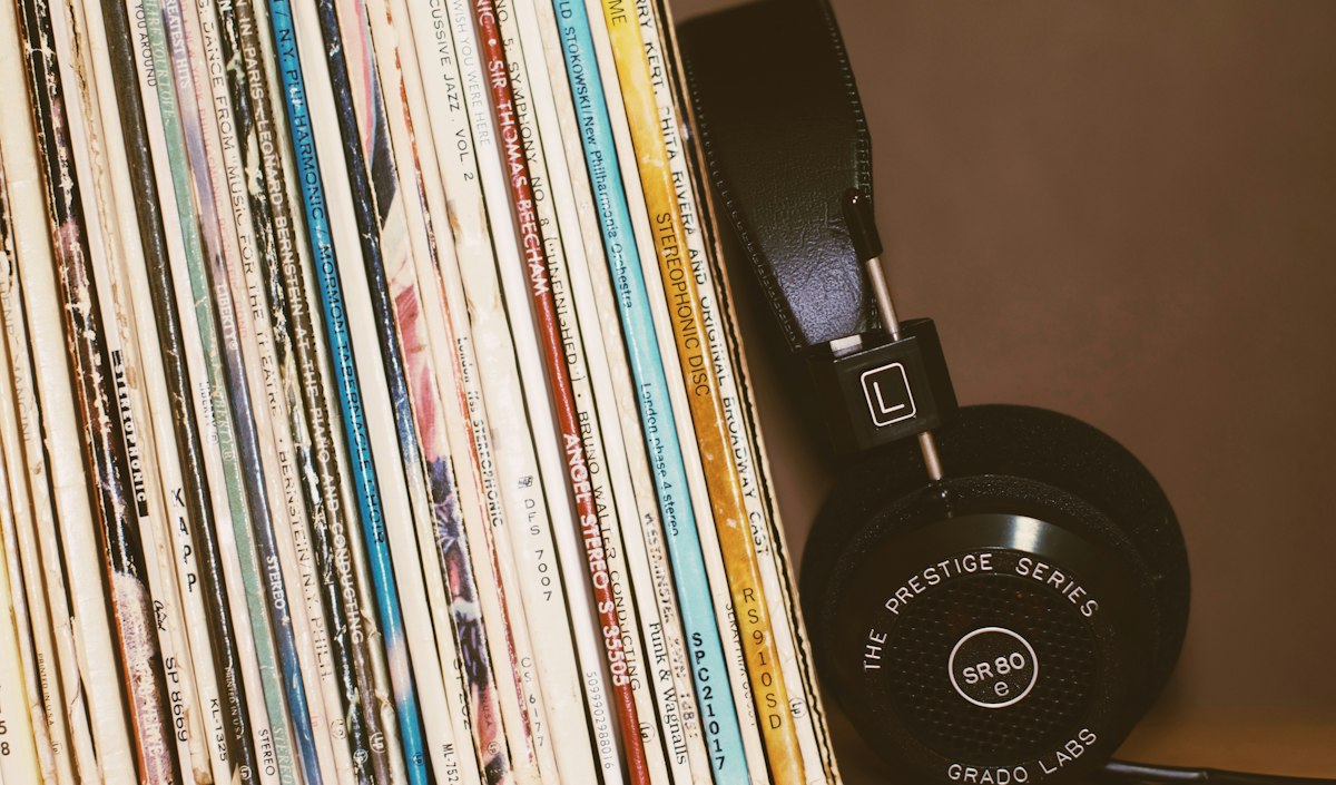 A row of vintage vinyl records beside a pair of headphones
